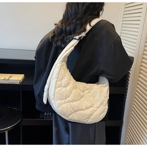Detailed macro view of white quilted crescent bag with adjustable black strap and buckle