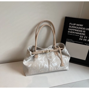 Detailed close-up of large beige tote bag featuring abstract lettering and brown handles