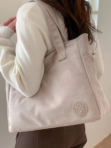 Minimalist beige suede tote bag with large capacity and soft strap shown on shoulder