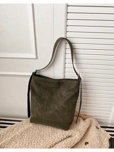 Detail of olive green matte leather tote bag with logo patch on a cozy fleece blanket