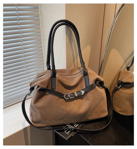 Close-up of brown suede tote bag with black strap accents and elegant silver metal hardware