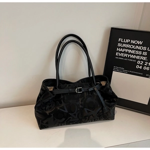 Detail of black textured tote bag featuring slender handles and silver buckle hardware