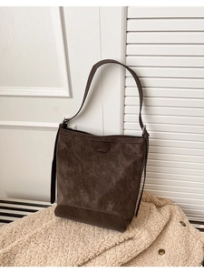 Detailed close-up of dark brown bucket bag showing matte leather texture and logo tag