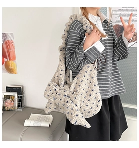 Close-up of beige plush shoulder bag with floral bow and soft fleece texture