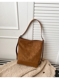 Close-up of brown vintage leather bucket bag with brand label on soft beige wool coat
