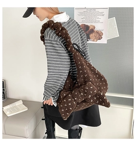 Close-up of fluffy brown plush shoulder bag with white polka dots and bow detail
