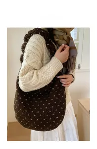 Dettaglio della borsa tote in peluche marrone scuro a pois bianchi su una modella