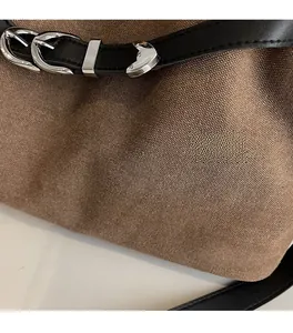 Macro detail of brown canvas fabric texture with black leather strap and silver buckle