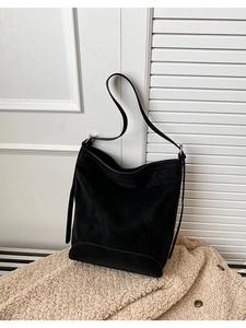 Detail shot of black hobo bag in suede texture with slim shoulder strap on soft faux fur