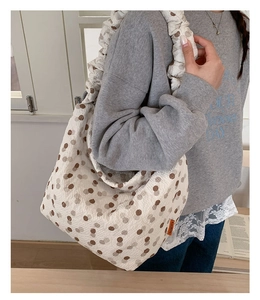 Detail of white bubble texture tote bag with brown polka dots and ruffled strap