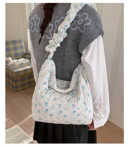 Detail of white quilted tote bag with blue polka dots and a stylish ruched shoulder strap
