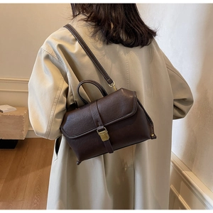 Details der dunkelbraunen Vintage-Umhängetasche mit weißen Kontrastnähten an einem Modell