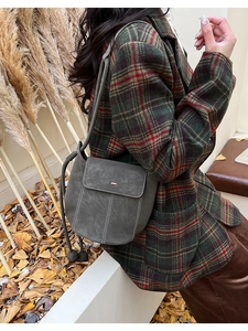 Detail of grey suede bucket bag with contrast stitching styled with a winter wool coat