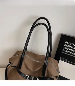 Detail view of brown canvas tote with black leather strap and silver buckle hardware