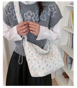 Quilted blue polka dot tote bag with wide shoulder strap shown in a lifestyle setting
