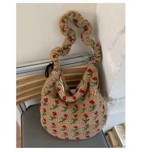 Dettaglio della borsa hobo in peluche con motivi floreali a rose rosse e manico ondulato