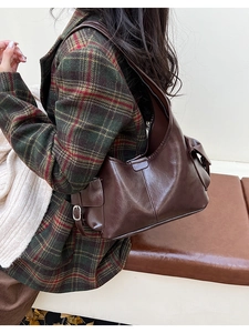 Detailed side view of dark brown faux leather underarm bag with metal buckle and side pocket