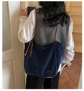 Detail of vintage denim tote bag with brown woven rope handle and fringe accent