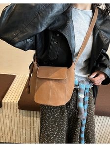 Detail of vintage brown bucket bag with contrast stitching and adjustable shoulder strap