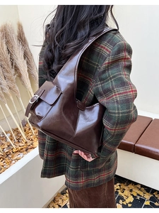 Detail view of a dark brown shoulder bag with a vintage metallic buckle side pocket