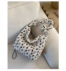 Detailed view of white polka dot quilted tote bag with ruffled cloud-like shoulder strap