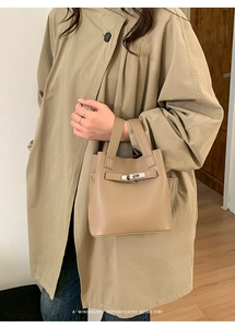 Close-up of khaki pebbled leather bucket bag with classic turn-lock strap detail
