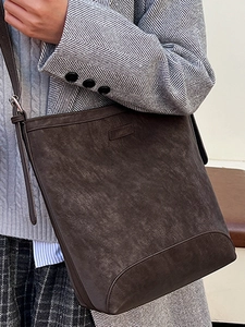 Retro dark brown crossbody bucket bag in matte leather worn with a vintage grey suit