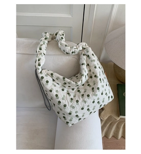 Detailed close-up of beige quilted fabric with green polka dots and ruffle shoulder strap
