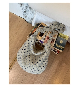 Dettaglio della trama della borsa tote in sherpa bianco con stelle blu accanto ai libri