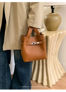 Detailed shot of caramel brown lychee leather handbag with elegant silver twist lock hardware