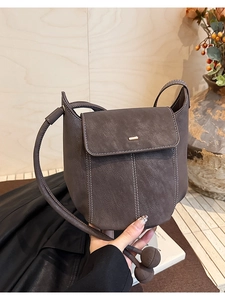 Detail of dark brown leather bucket bag with white contrast stitching and gold buckle