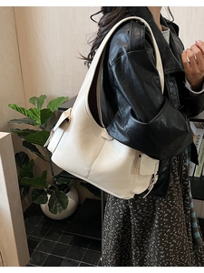Chic beige hobo shoulder bag with side buckle pocket styled with a black leather jacket