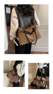 Detail view of a large brown canvas tote bag with black leather straps and buckle decor