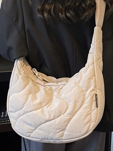 Minimalist beige quilted crescent shoulder bag featuring stylish wavy stitching patterns
