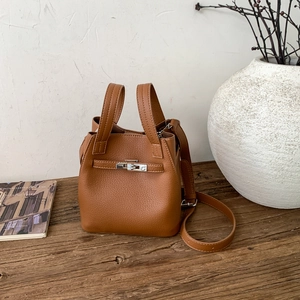 Detailed macro of brown lychee grain leather handbag with gold metal lock on wooden table