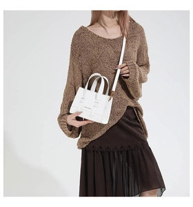 Mini white leather crossbody bag with top handles and gold logo shown on model