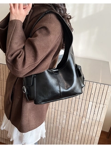 Detail of minimalist black hobo bag showing faux leather texture and silver buckle