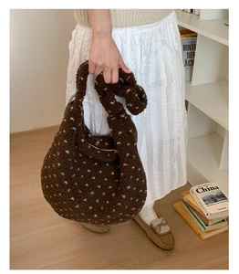Dettaglio borsa tote in peluche marrone con manico a nodo e motivi a stella bianchi