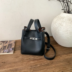 Detailed close-up of a black lychee grain leather bucket bag with silver buckle on wood