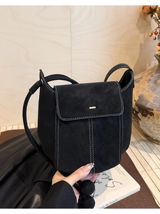 Detail of black leather bucket bag featuring white contrast stitching and gold metal hardware
