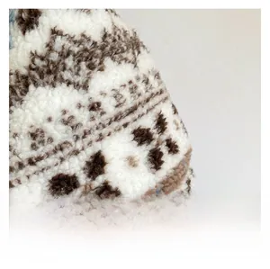 Gros plan sur le tissu sherpa beige duveteux avec des motifs jacquard géométriques bruns