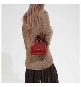 Detailed view of glossy red patent leather shoulder bag with sleek metallic logo detail