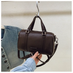 Close-up of dark brown lychee leather Boston bag with silver hardware and dual handles