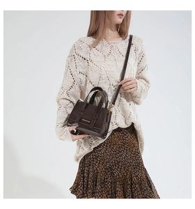 Detail view of small brown faux leather tote bag with gold lettering and slim strap