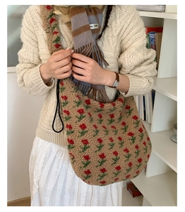 Dettaglio della borsa tote in peluche con motivo a rose rosse e tracolla nera intrecciata