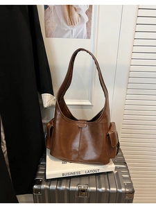 Close-up of a brown vintage faux leather tote bag with glossy finish on a silver suitcase