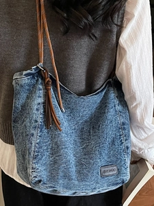 Large denim tote bag with woven rope straps and leather tassel detail for casual style
