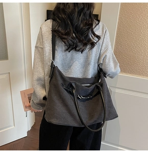 Detail of dark grey canvas tote bag with black leather straps and pleated design texture