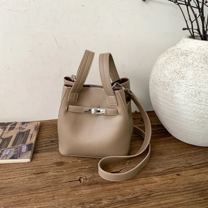 Detail of light khaki lychee pattern leather bucket bag with silver metal twist lock
