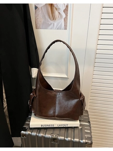 Detail of dark brown glossy PU leather tote bag featuring side flap pockets and wide strap